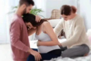 Pregnant woman receiving support from partner and doula during labor