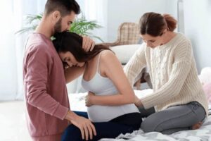 Pregnant woman receiving support from partner and doula during labor