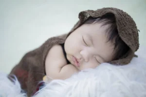 Newborn baby sleeping, wearing brown clothing
