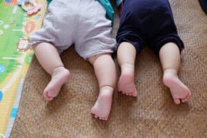 image of bottom half of two babies face down on playing mats